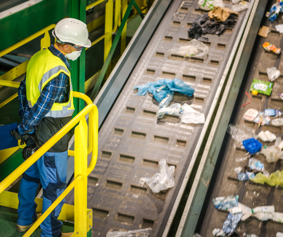 Employee wearing face mask and hard hat overseeing waste and recycling process