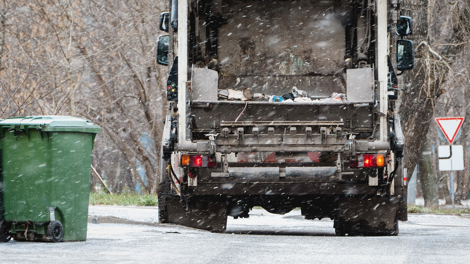 Garbage truck waste removal in residential area in winter snow